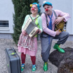 Clownin und Clown mit Musikinstrumenten und Koffer